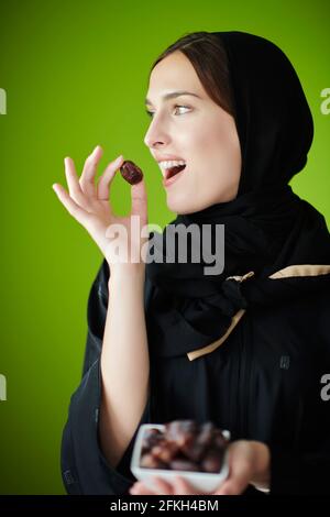 Young muslim girl wearing traditional muslim clothes holding dried dates Stock Photo