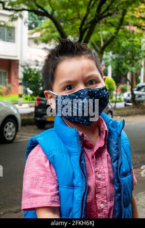 Medellin, Colombia - March 28 2021: Little Latin Boy Wearing a Blue Face Mask Outside Stock Photo