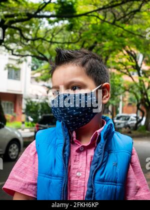 Medellin, Colombia - March 28 2021: Little Latin Boy Wearing a Blue Face Mask Outside Stock Photo