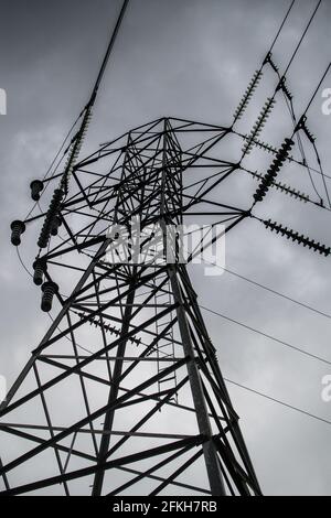 Looking up at a transmission tower / power tower on a grey, cloudy day. Stock Photo