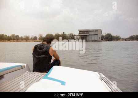Hispanic man sitting, calm, in a boat on lake at noon Stock Photo
