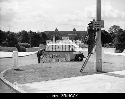 File photo dated 1/5/1948 of workers putting up signs in London to direct people to the various venues associated with the Olympic Games. Wembley Park, London's globally renowned entertainment district, has undergone significant change over the past 70 years, with the newly built Olympic Steps signifying the final piece of the puzzle in the development of the iconic Olympic Way, also known as 'Wembley Way'. Issue date: Sunday May 2, 2021. Stock Photo