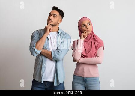 Difficult Choice. Portrait Of Pensive Arabic Couple Standing On Grey Background Stock Photo