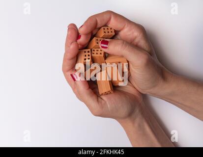 Two female hands with a lot of small toy bricks on a white background. Stock Photo