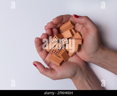 Two female hands with a lot of small toy bricks on a white background. Stock Photo