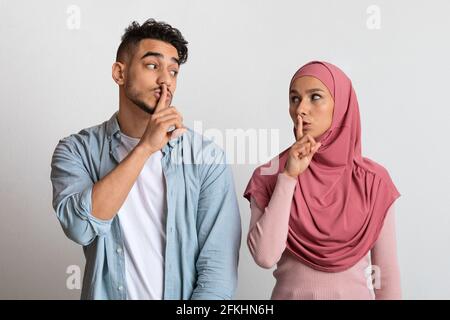 Don't Say Anybody. Arab Man And Woman In Hijab Making Silence Gesture Stock Photo