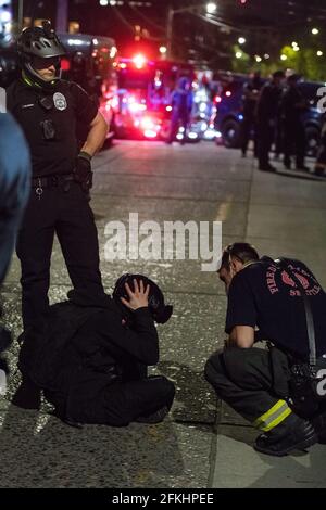 Seattle, USA. 1st May, 2021. Late in the evening a protestor being treated by the fire department near the East Precinct after being thrown off the hood of a vehicle accelerating through the intersection of 12th and Pine. Protestors were on Capitol Hill marching in a May Day protest. Credit: James Anderson/Alamy Live News Stock Photo