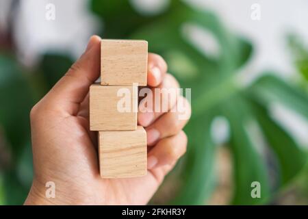 Blank wooden cube that you can put text or icon on in hand hold background. Stock Photo