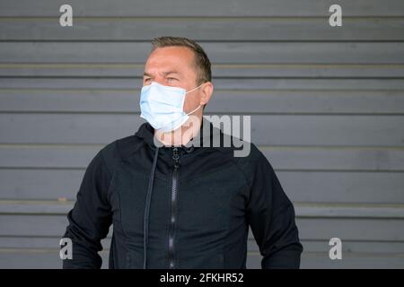 Portrait of a middle-aged man wearing protection mask while looking away and thinking of future during Covid-19 pandemic Stock Photo