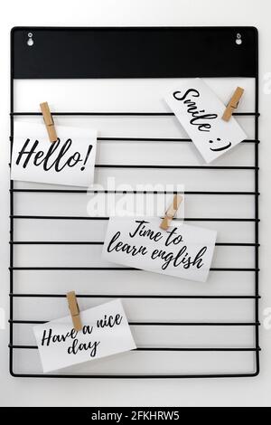 Words of the English language written on sheets of paper attached to a metal hanger with clips Stock Photo
