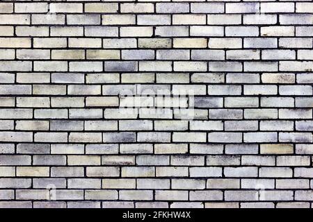 A pale light yellow brick wall with shades of blue Stock Photo