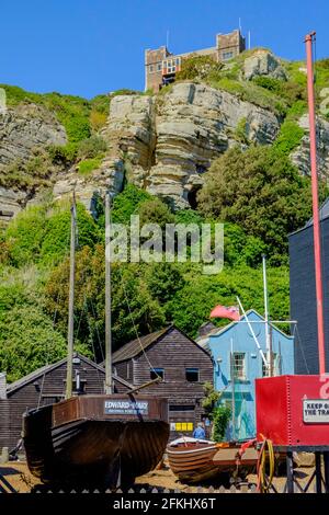 Staycation idea. Old wooden fishing boat Edward & Mary, beached at The Stade, Hastings, with the East Hill Lift, other buildings & smaller boat. UK Stock Photo