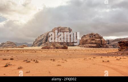 Rocky massifs on red orange sand desert, overcast sky in background - typical scenery in Wadi Rum, Jordan Stock Photo