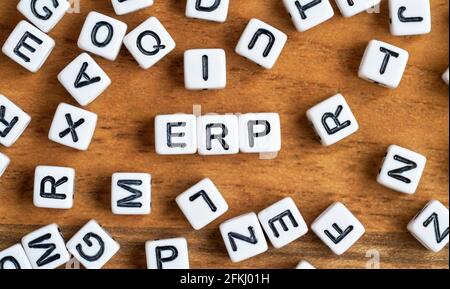 Small white and black bead cubes on wooden board, letters in middle spell ERP - Enterprise resource planning concept Stock Photo