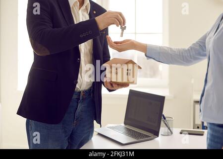Cropped shot of real estate agent holding small house model and giving key to client Stock Photo