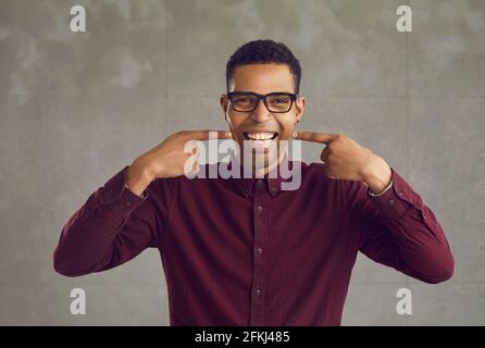 Young african american man pointing showing white teeth smile studio shot Stock Photo