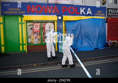 Forensic officers enter a shop on Waterloo Road, Smethwick, after a murder investigation has been launched when a teenager was chased into a shop and stabbed. West Midlands Police said the 17-year-old victim was found with knife wounds by a white Ford Focus which had crashed in the street on Saturday. The force said it is understood that 10 minutes before the victim was taken to hospital, he was chased into a shop in Waterloo Road and attacked with a knife. He was taken to hospital after being found with injuries but was pronounced dead around an hour later. Picture date: Sunday May 2, 2021. Stock Photo