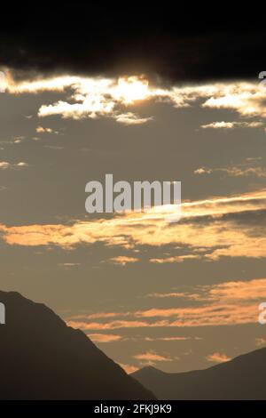 The Sun shining through clouds over mountains near Anchorage Alaska USA Stock Photo