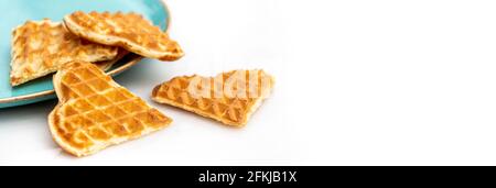 Heart shaped waffles standing scattered in green plate on white marble table Stock Photo