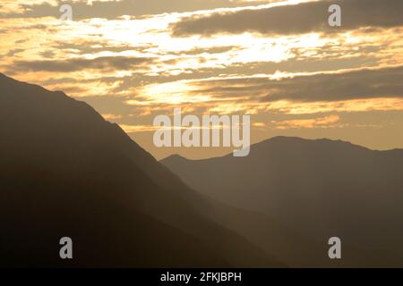 The Sun shining through clouds over mountains near Anchorage Alaska USA Stock Photo