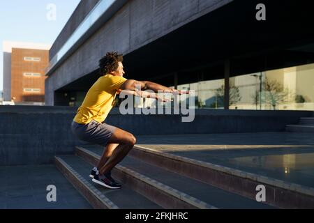 Black man doing squats with jumping on a step. Stock Photo