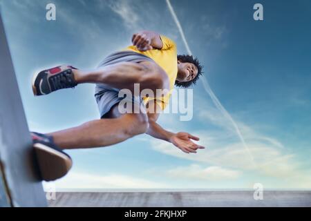 View from below of black man jumping on his run. Stock Photo