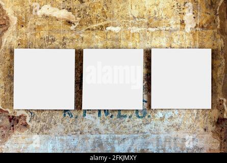 Three empty painting frames on old weathered grunge wall Stock Photo