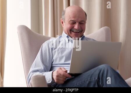 Senior man connected on internet with laptop at home Stock Photo