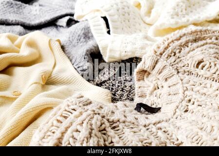 Bunch of knitted warm pastel color sweaters with different knitting patterns laid in messy pile, clearly visible texture. Stylish fall / winter season Stock Photo