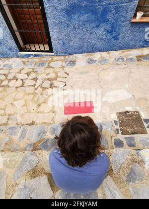 A high-angle shot of an unrecognizable boy sitting on stairs in old town Finestrat, Alicante, Spain Stock Photo