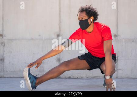 Afro athletic man stretching legs before exercise. Stock Photo