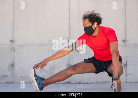 Afro athletic man stretching legs before exercise. Stock Photo
