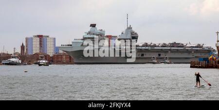 Portsmouth, England, UK. 2021. HMS Queen Elizabeth an aircraft carrier  with escorting tugs departs Portsmouth Harbour passing the colourful apartment Stock Photo