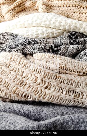 Bunch of knitted warm pastel color sweaters with different knitting patterns laid in messy pile, clearly visible texture. Stylish fall / winter season Stock Photo