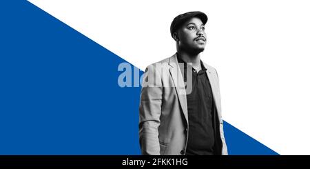 African american man standing against dual tone background. Man in formal suit and cap looking away. Stock Photo