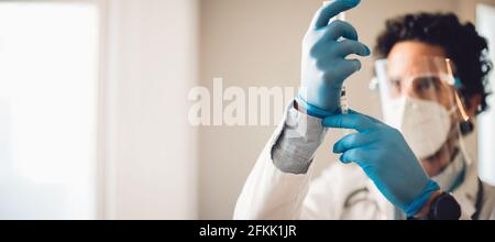 Hands of a frontline worker preparing vaccine syringe. Doctor making a vaccine injection ready for giving vaccination. Stock Photo