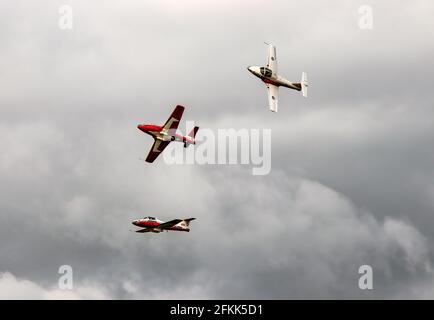 Red and white jets flying in formation through a gray sky with a summer storm about to begin Stock Photo