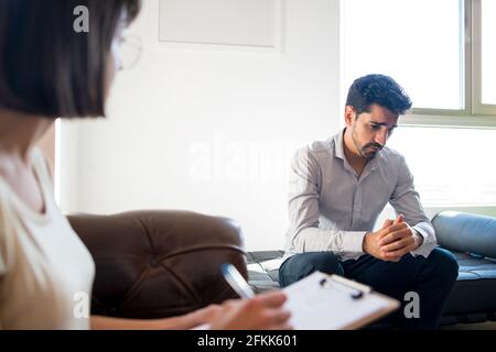 Psychologist taking notes during therapy session. Stock Photo