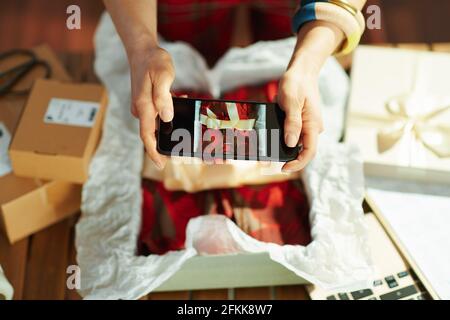 Closeup on middle aged small business owner woman making product photo with smartphone in the office. Stock Photo