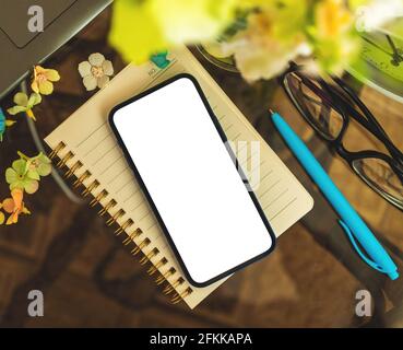 Smartphone with blank mockup screen on glass table, lady workspace, home interior concept with copy space, top view Stock Photo
