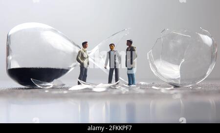 miniature people. figures people stand near the broken hourglass. business crisis. stop time process Stock Photo