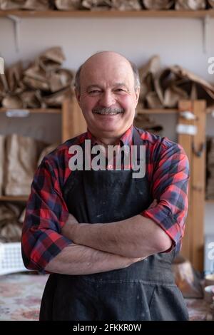 Senior happy hispanic craftsman standing in studio. Stock Photo