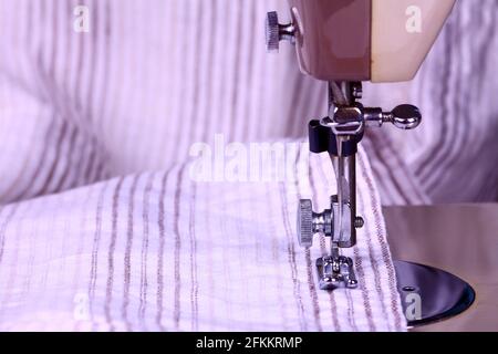 Striped cotton material and a vintage sewing machine in close up Stock Photo