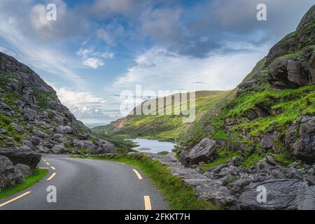 Winding road running through Gap of Dunloe with view on lake and green hills, Black Valley, MacGillycuddys Reeks mountains, Ring of Kerry, Ireland Stock Photo