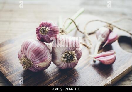 Rustic style garlic on vintage wooden background. Fresh young peeled purple garlic. Stock Photo