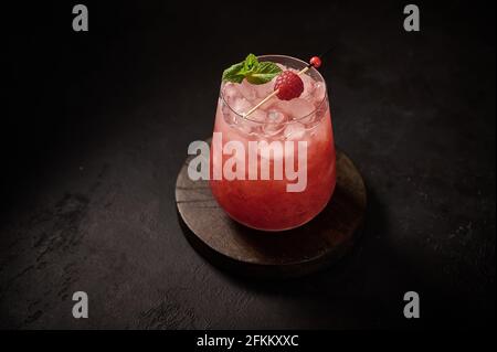 Homemade fresh iced lemonade with raspberry and mint on a wooden background. Summer healthy drink. Copy space  Stock Photo