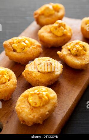 Homemade Deep-fried Deviled Eggs with Paprika on a Rustic Wooden Board, side view. Stock Photo