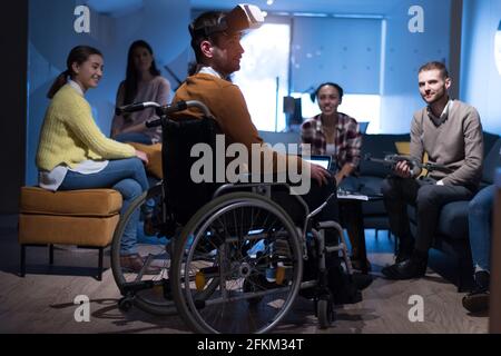 Disabiliti concept. Diverse group of architects witho one in wheelchair working in coworking office using modern technology. Stock Photo