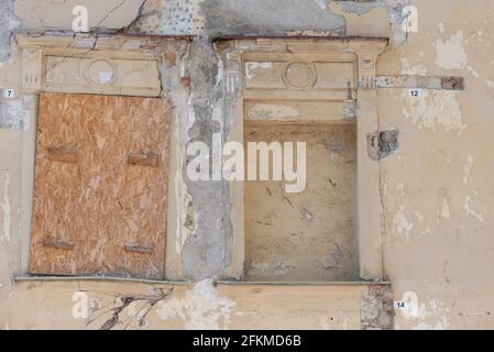 The windows are bricked up in the house. One window is completely bricked up, the second is covered with plywood. Stock Photo