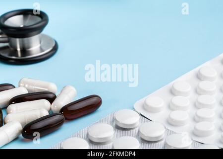 Assorted brown and white capsules, stethoscope, blister isolated on blue background. Nutritional supplements for weight loss and energy, dietary aids Stock Photo
